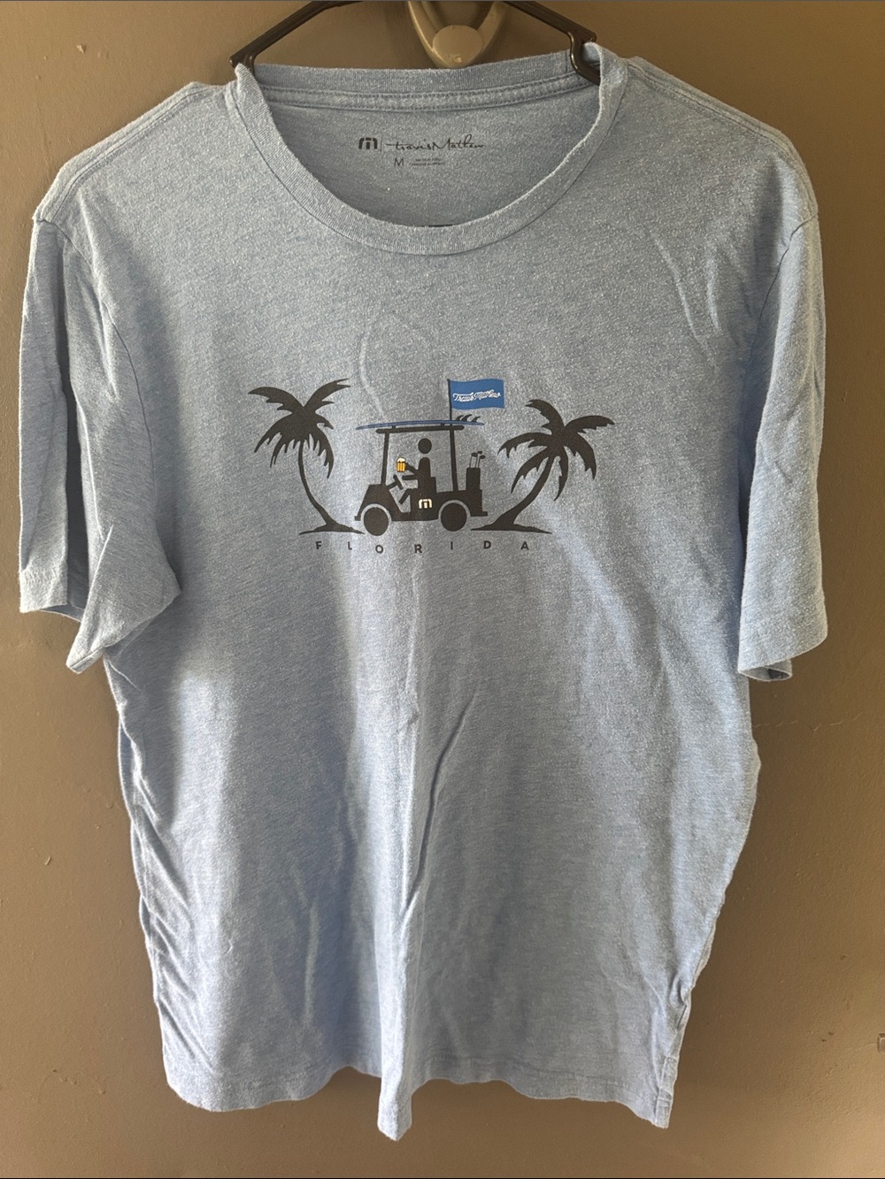 Travis Mathew Light Blue Tee with Palm & Golf Cart Graphic